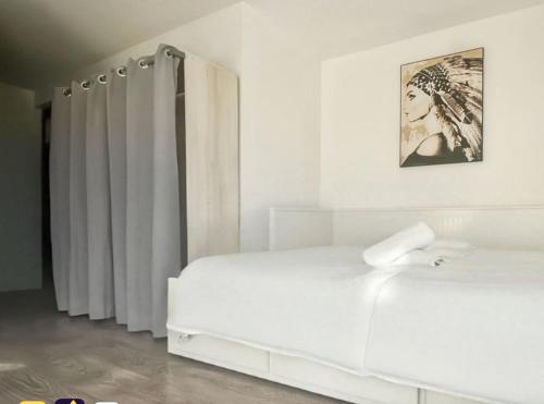 - une chambre blanche avec un lit et des rideaux blancs dans l'établissement Le Petit Gaudois, à La Gaude