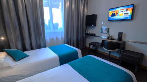 a hotel room with two beds and a desk and a television at Hôtel d'Orléans in Orléans