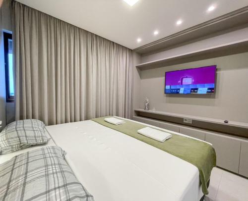 a bedroom with two beds and a flat screen tv at Modernidade e Luxo no 30º Andar in Campo Grande