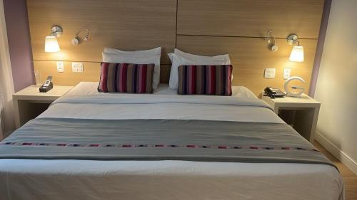 a large bed in a hotel room with two pillows at flat em Santos quadra da praia in Santos
