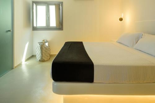 a bedroom with a bed with a black and white blanket at Tataki Family Hotel in Fira