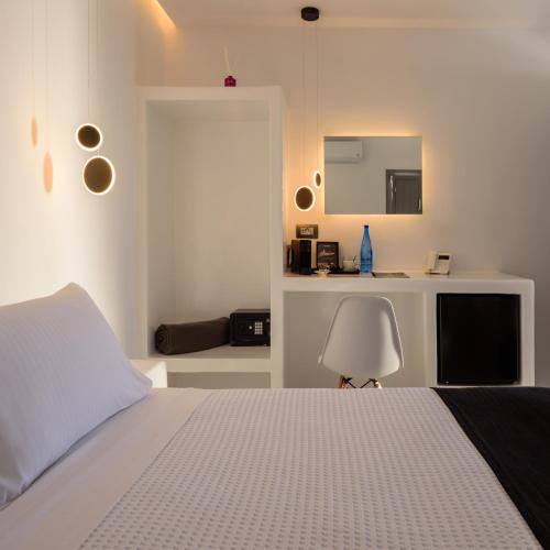 a white bedroom with a bed and a table at Tataki Family Hotel in Fira