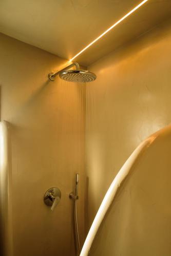 a shower with a shower head in a bathroom at Tataki Family Hotel in Fira