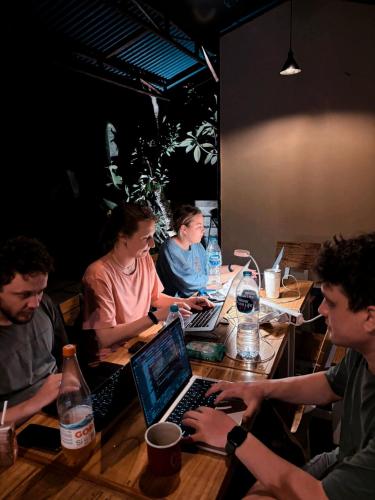 a group of people sitting around a table with a laptop at Guest House 88 Pandawa in Nusa Dua