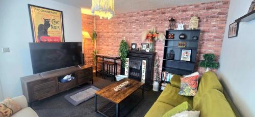 a living room with a television and a brick wall at The Hideaway Cottage Feel Patio Central Parking in Southport