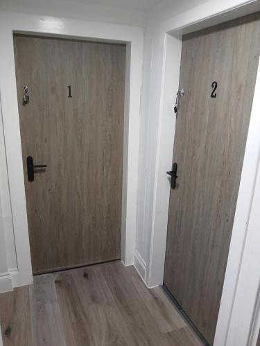 two doors in a room with wooden floors at The Hideaway Inverurie in Inverurie