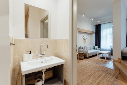 a bathroom with a sink and a living room at Apartmán CityPulse in Banská Štiavnica