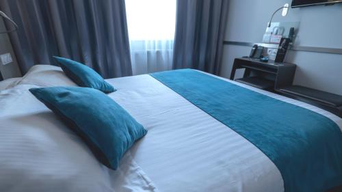 a bedroom with a large bed with blue pillows at Hôtel d'Orléans in Orléans