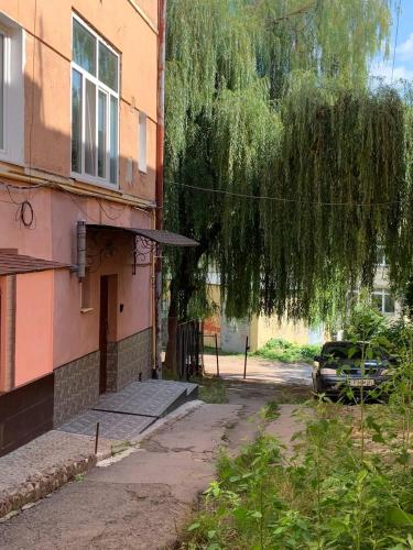 a tree hanging over a building with a car parked next to it at VEL-Шевченка in Chernivtsi