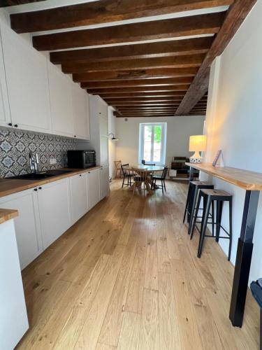 Il comprend une cuisine et une salle à manger avec des placards blancs et des plafonds en bois. dans l'établissement Presbytère de Solterre, à Solterre