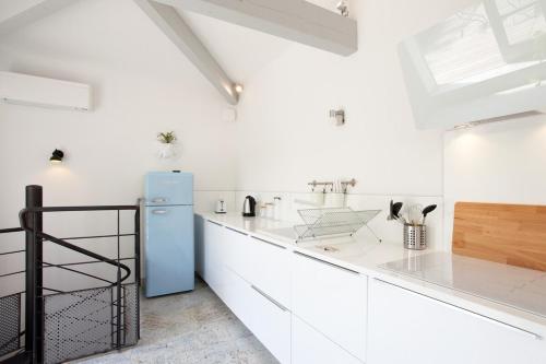 La cuisine est équipée de placards blancs et d'un réfrigérateur bleu. dans l'établissement Appartement L'Armande, à Arles