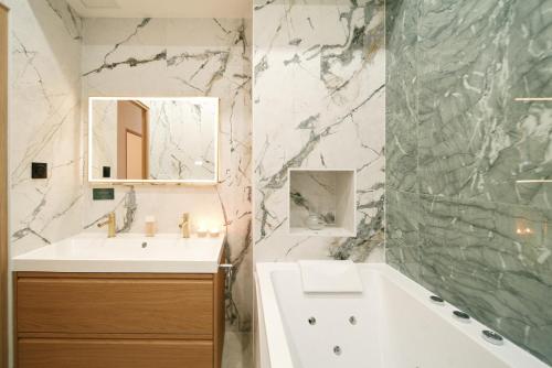 une salle de bain avec un lavabo, une baignoire et un miroir dans l'établissement Lavie Maison Central AC Hot Tub, à Paris