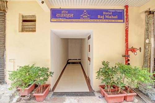 a hallway of a building with potted plants and a sign at Hotel O Raj Mahal in Turambhe