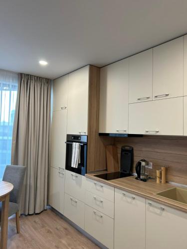 a kitchen with white cabinets and a sink and a table at Skyline studio 44 in Varna City