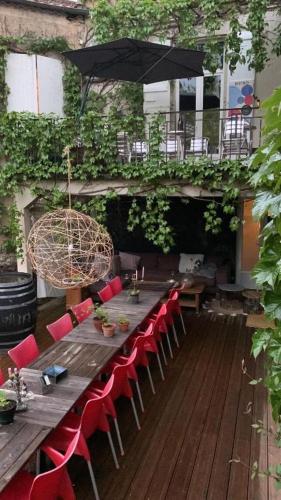 a long wooden table with red chairs and an umbrella at Pause ton sac # Relais Saint Jacques #Venez dormir chez nous in Condom