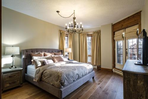 une chambre avec un lit et un lustre dans l'établissement Equinox Condo On-Resort Luxury Direct Ski Access Stunning View, à Mont-Tremblant