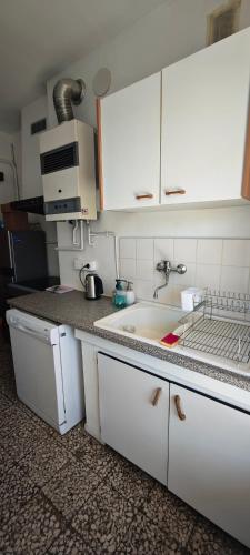 une cuisine avec des armoires blanches et un évier dans l'établissement F2 Entrée de la ville Vue Mer, à Ajaccio