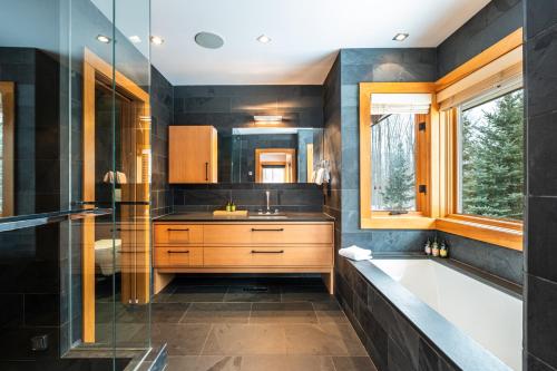 ein Badezimmer mit Badewanne und Waschbecken in der Unterkunft Grand Foret Villa Luxurious Chalet with Hot Tub and Outdoor Firepit in Mont-Tremblant