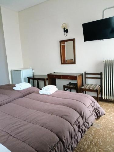 a bedroom with two beds and a table and a mirror at Ermis in Loutra Ipatis