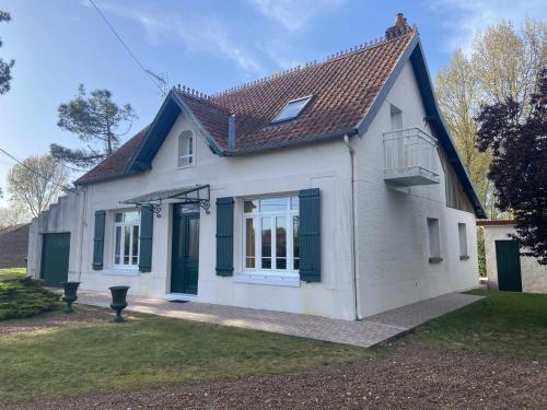 a small white house with green shutters on it at Mer et Campagne, maison entourée d'un jardin privé in Quend