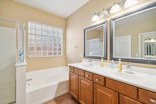a bathroom with two sinks and a bath tub and a tubermottermott at Gilbert Getaway in Gilbert
