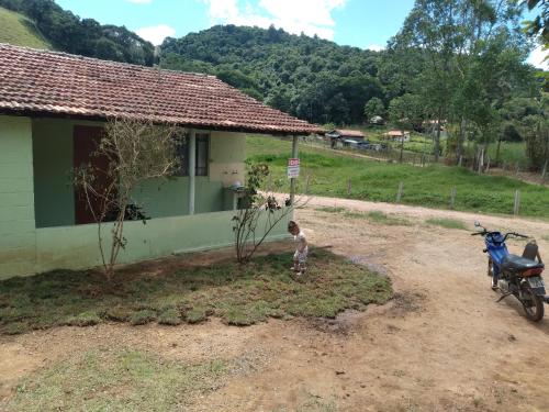 a child standing in front of a house with a motorcycle at Casinha Verde in Camanducaia