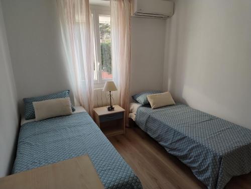 deux lits dans une petite pièce avec une fenêtre dans l'établissement la plage en face , 2 chambres clim parking, au Pradet