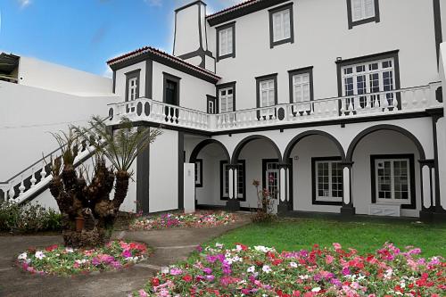 a large white house with flowers in the yard at Casa Senhor da Pedra in Vila Franca do Campo
