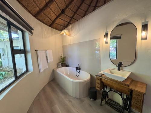 a bathroom with a tub and a sink and a mirror at Heritage View Birding Retreat in Delareyville