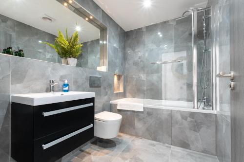 a bathroom with a sink and a shower and a toilet at Elegant Apartments in Staines l Free Onsite Parking in Staines