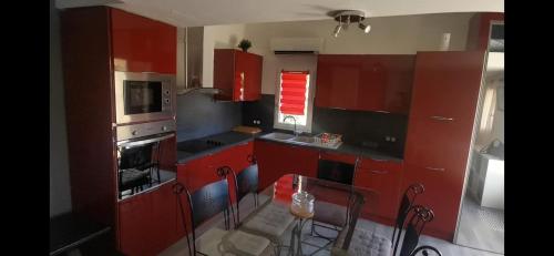 une cuisine avec des armoires rouges et une table et des chaises dans l'établissement Petite maison à la campagne, à Forcalqueiret