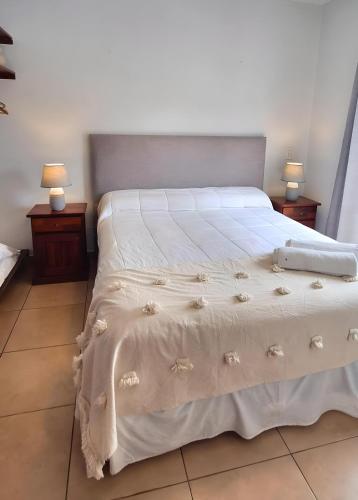 a bedroom with a white bed with two night stands at Las Tulmas Apartamentos Salta in Salta