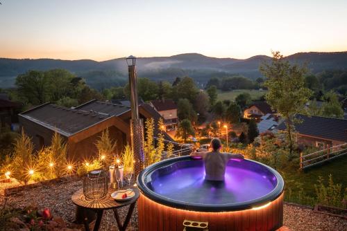 a man sitting in a jacuzzi tub on a patio at Ferienwohnung Weitblick in Bruchweiler-Bärenbach