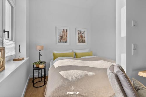 a white bedroom with a bed and a side table at Ferienwohnung Kleine Welle Westerland auf Sylt in Westerland (Sylt)