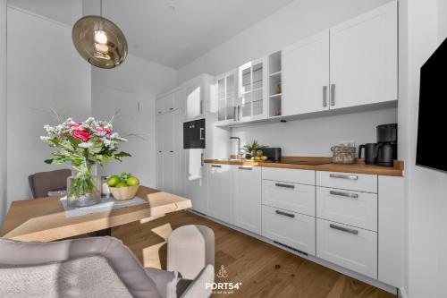 a kitchen with white cabinets and a table with flowers at Ferienwohnung Kleine Welle Westerland auf Sylt in Westerland (Sylt)