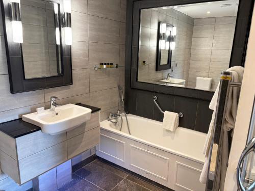 a bathroom with a sink and a tub and a mirror at The Belsfield Hotel in Bowness-on-Windermere