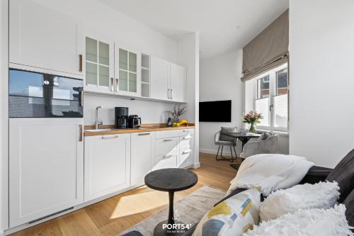 Il comprend une cuisine et un salon avec des placards blancs et un canapé. dans l'établissement Ferienwohnung Leichte Brise Westerland auf Sylt, à Westerland