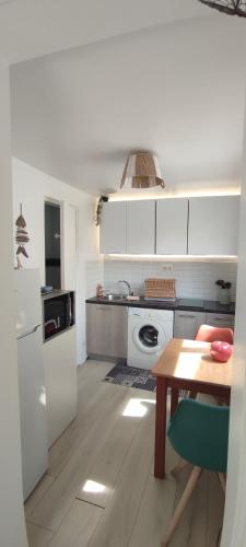 une cuisine avec des armoires blanches, une table et une cuisinière dans l'établissement Nid de verdure à 15 minutes centre et plage, au Havre