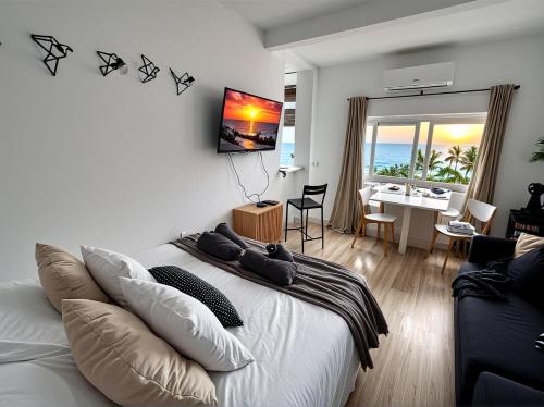 Un dormitorio con una cama blanca y una sala de estar. en Beachfront Studio ,The View Calahonda, Panoramic Sea Views, en Mijas Costa