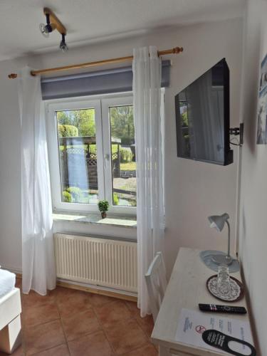a room with a window with white curtains and a desk at Hotel Panorama in Wees