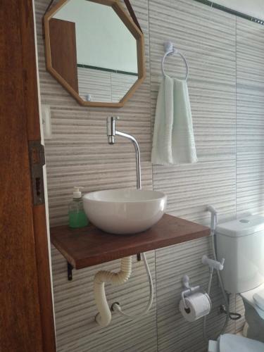 a bathroom with a sink and a mirror and a toilet at Recanto Verde - Praia de Santo Antônio in Diogo