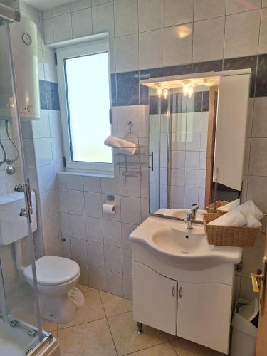 a bathroom with a sink and a toilet and a window at Apartments Dalmacija in Podstrana