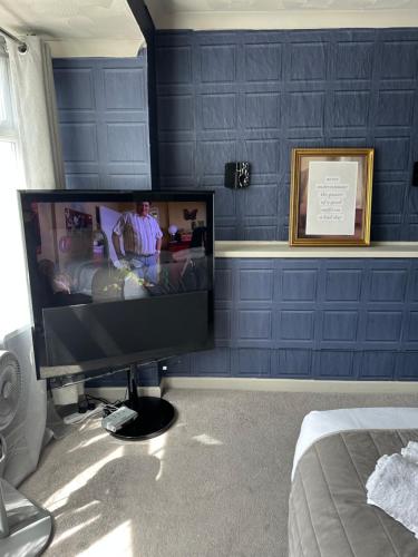 a television in a bedroom with a blue wall at The Q Hotel in Shanklin
