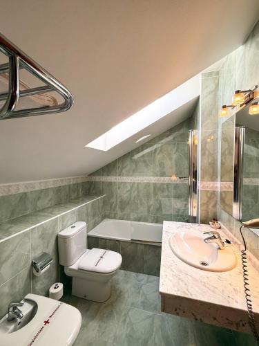 a bathroom with a toilet and a sink and a tub at Hotel Verdemar in Ribadesella