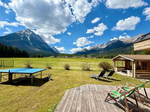 a picnic table and chairs in a field with mountains at Apartmenthaus Brigitte in Leutasch