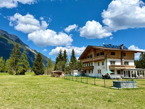 a house in a field with mountains in the background at Apartmenthaus Brigitte in Leutasch