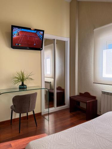 a bedroom with a glass table with a television on the wall at Hotel Verdemar in Ribadesella