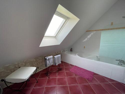 La salle de bains mansardée est pourvue d'une baignoire et d'une fenêtre. dans l'établissement Domaine de la Maison Neuve, à Saint-Jean-Saint-Germain