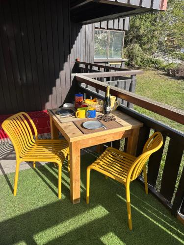 - une table en bois et 2 chaises sur la terrasse dans l'établissement Le Nid Douillé du Crêt, parking et terrasse, à Val dʼIsère