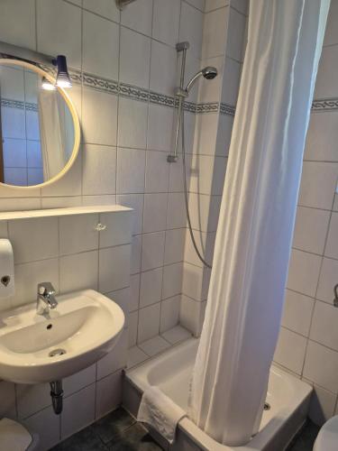 a white bathroom with a shower and a sink at Hotel Panorama in Wees